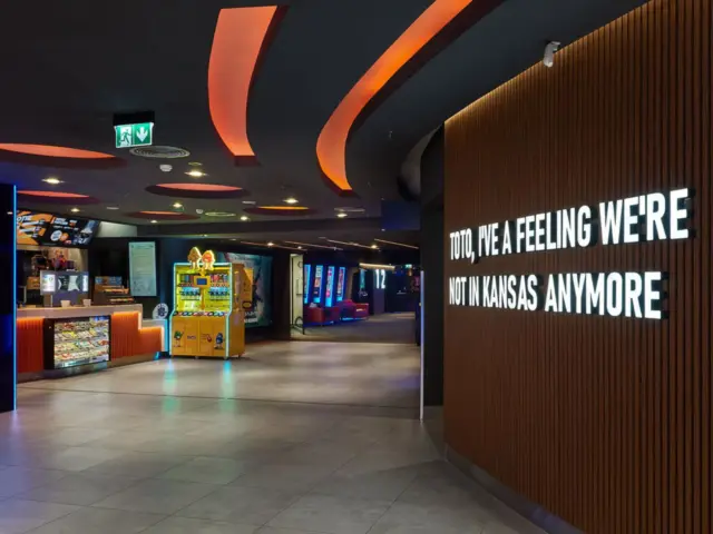 Litere volumetrice albe redau un citat pe peretele cu lamele din holul cinematografului.