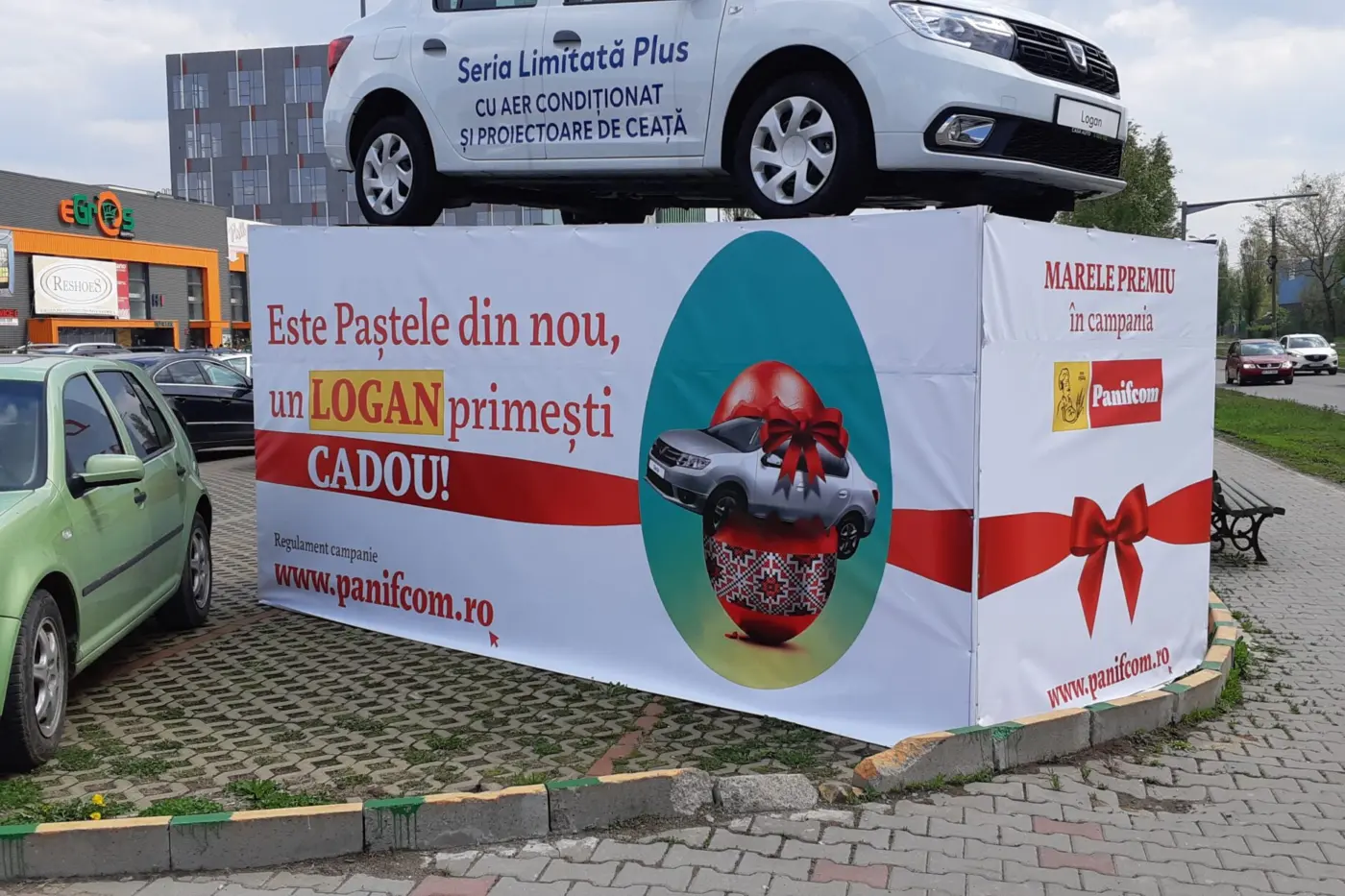 Banner Panifcom pentru campania de Paște, montat pe structura de expunere a unui automobil Logan.