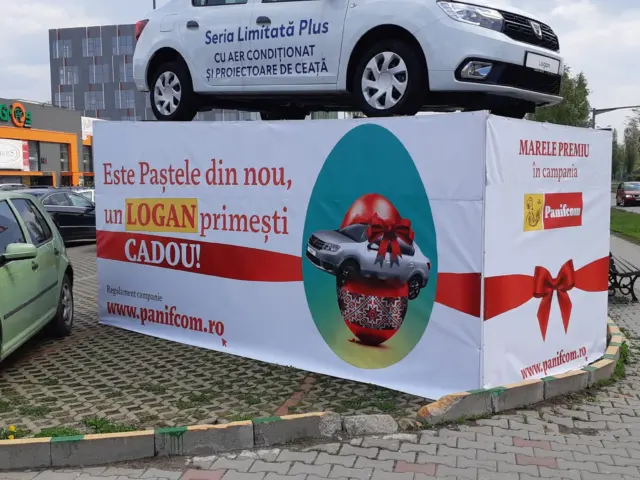 Banner Panifcom pentru campania de Paște, montat pe structura de expunere a unui automobil Logan.
