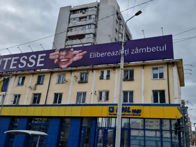 Banner mov pentru servicii dentare, montat pe acoperișul unei clădiri urbane
