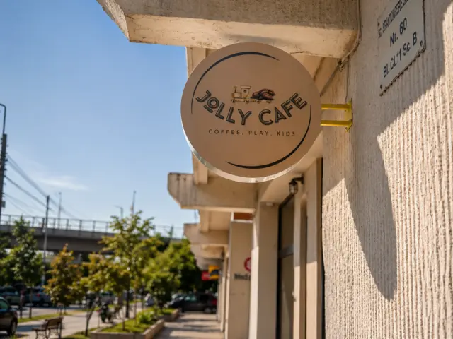 Round Jolly Cafe sign projecting from the building facade above the sidewalk.