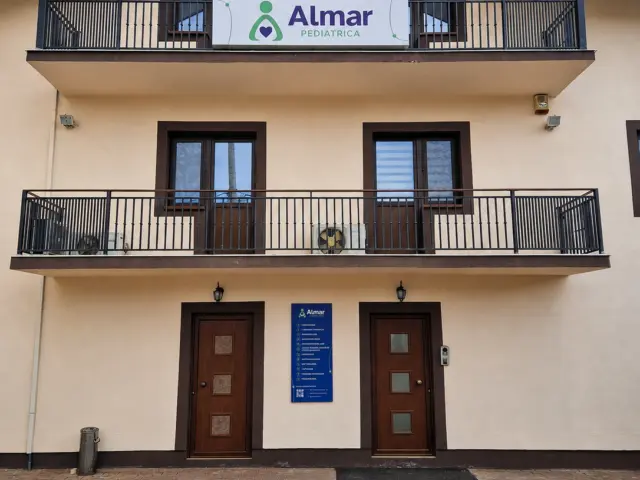 Almar Pediatrica sign mounted on the upper balcony railing above the building entrance.