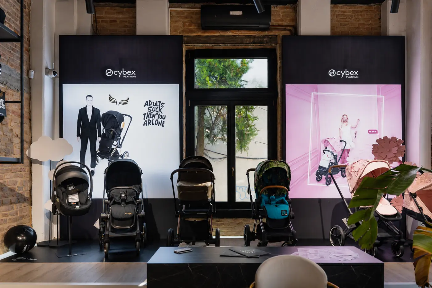 Două reclame luminoase Cybex Platinum, amplasate în showroom în spatele mai multor cărucioare pentru copii.