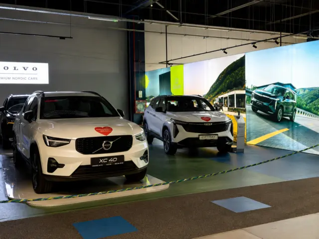Perete grafic luminos de mari dimensiuni, amplasat în spatele automobilelor expuse într-un spațiu interior.