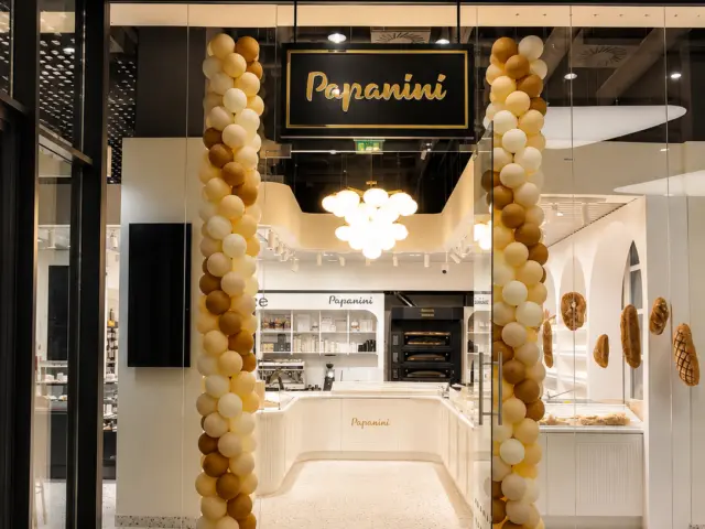 Hanging Papanini sign above the glass entrance, framed by decorative balloon columns.