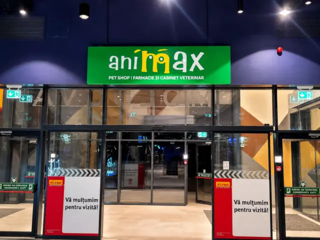Green illuminated Animax sign mounted above the glass doors of a commercial entrance.
