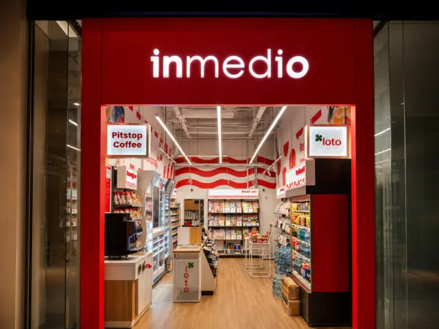 Litere luminoase inmedio montate pe frontul roșu, deasupra intrării deschise a magazinului.