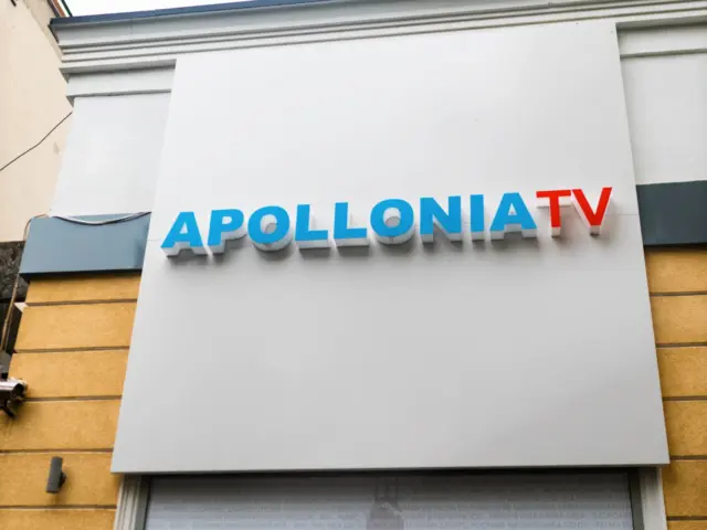 Litere volumetrice albastre și roșii APOLLONIA TV, montate pe fațadă deasupra unei ferestre.