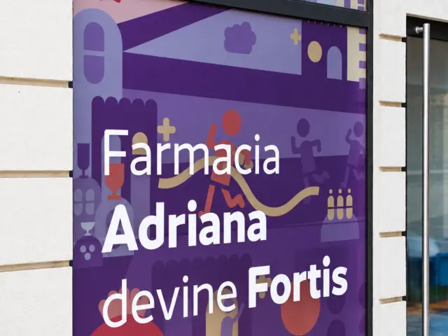 Vitrină arcuită cu grafică mov ilustrată și mesajul „Farmacia Adriana devine Fortis”.