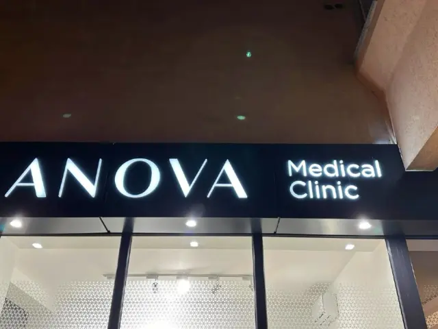 Litere luminoase ANOVA Medical Clinic, montate pe panoul negru deasupra intrării vitrate.