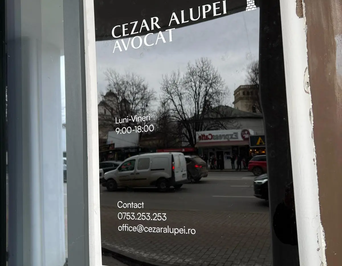 Placă informativă neagră Cezar Alupei Avocat, montată pe perete lângă o ușă vitrată.