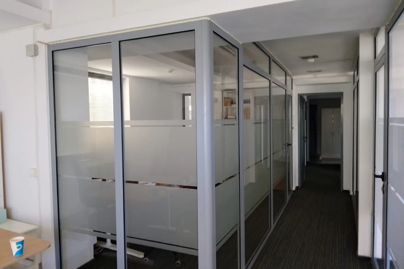 Autocolant mat aplicat pe compartimentări interioare din sticlă, cu benzi transparente orizontale.