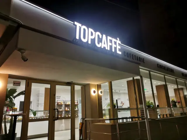 Litere volumetrice luminoase TOPCAFFÈ montate pe fațada cofetăriei și aprinse pe timp de noapte.