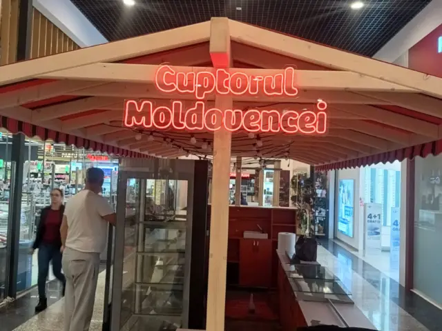Inscripția roșie „Cuptorul Moldovencei” din Neon Flex, montată frontal sub acoperișul unui chioșc interior.