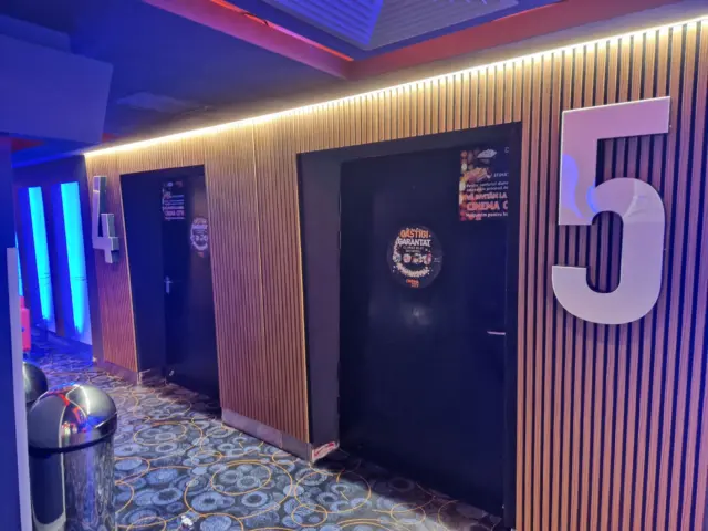 Numere volumetrice albe 4 și 5, montate pe pereții cu lamele ai coridorului Cinema City.