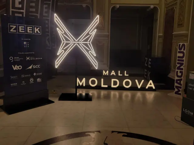 Emblema Mall Moldova conturată cu Neon Flex alb, expusă pe suport la evenimentul ZEEK.