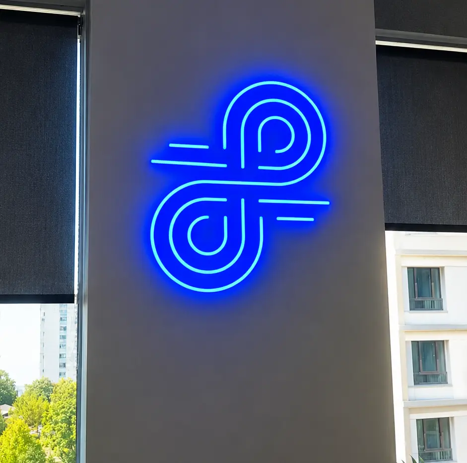 Semn albastru din Neon Flex, cu simbol geometric abstract, montat pe un perete gri între ferestre.