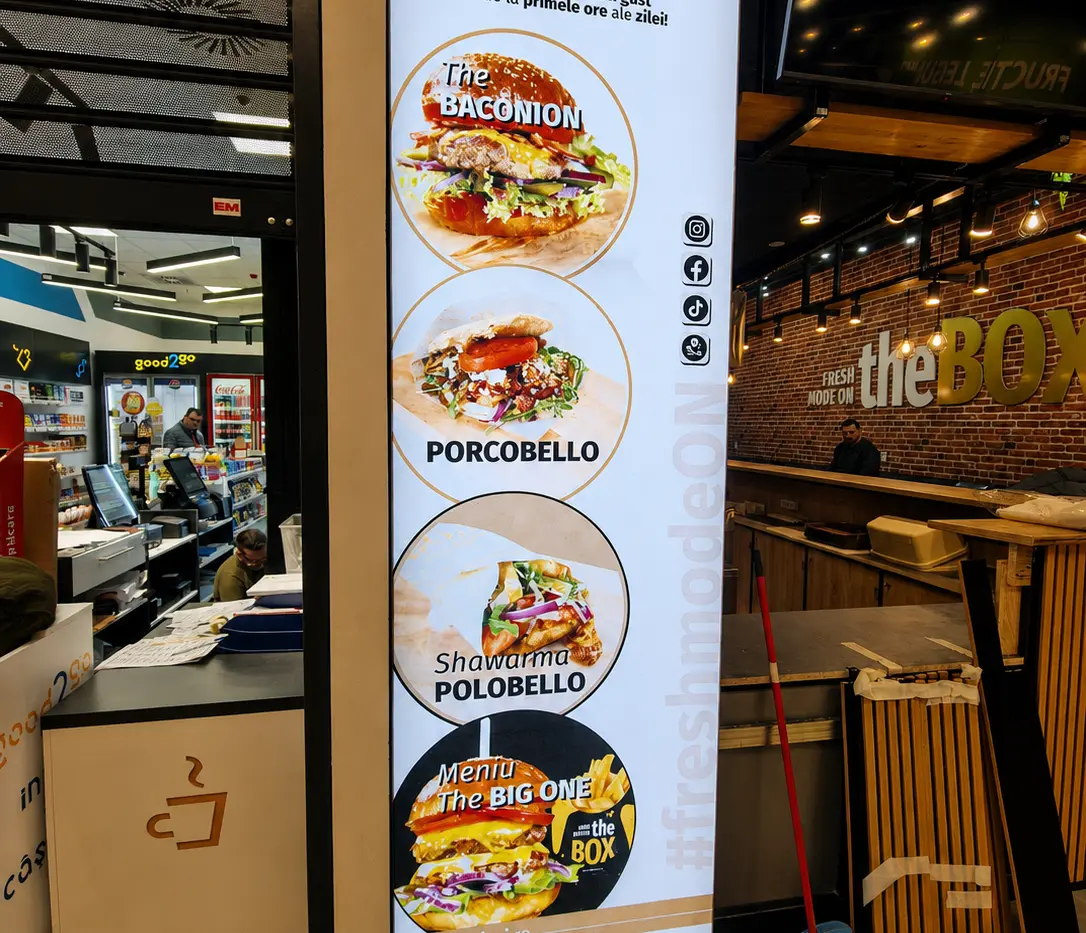 Panou publicitar luminos vertical the BOX, cu preparate din meniu, amplasat la intrarea în restaurant.