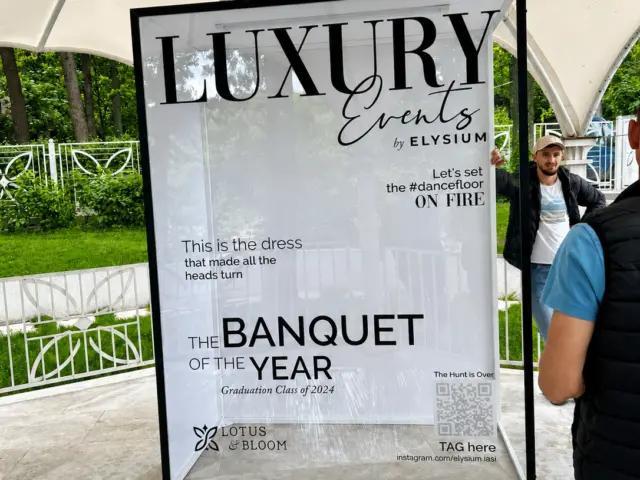 Fotobox personalizat Luxury Events by Elysium, cu ramă neagră și panou transparent, instalat sub un pavilion.
