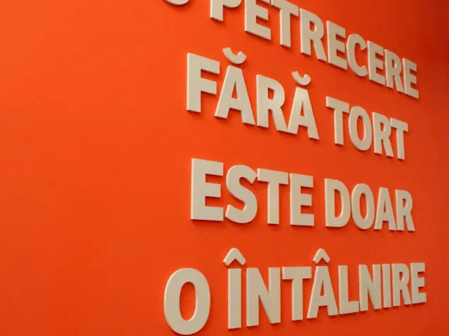 Mesajul „O petrecere fără tort este doar o întâlnire”, realizat din litere 3D albe pe un perete portocaliu.