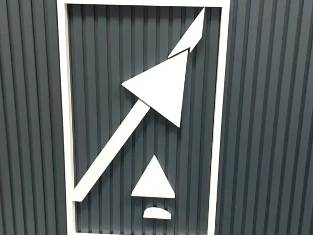 Sigla albă ALTEN și litere volumetrice montate pe un perete închis la culoare, cu riflaj vertical.