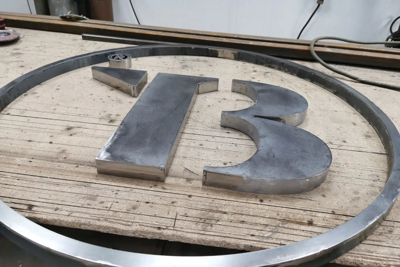Elemente volumetrice metalice formând numărul 13, așezate într-un cadru circular pe masa de lucru.