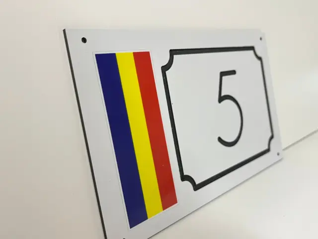 Plăcuță albă pentru numărul 5, cu tricolor vertical și chenar negru decorativ, sprijinită pe un fundal alb.