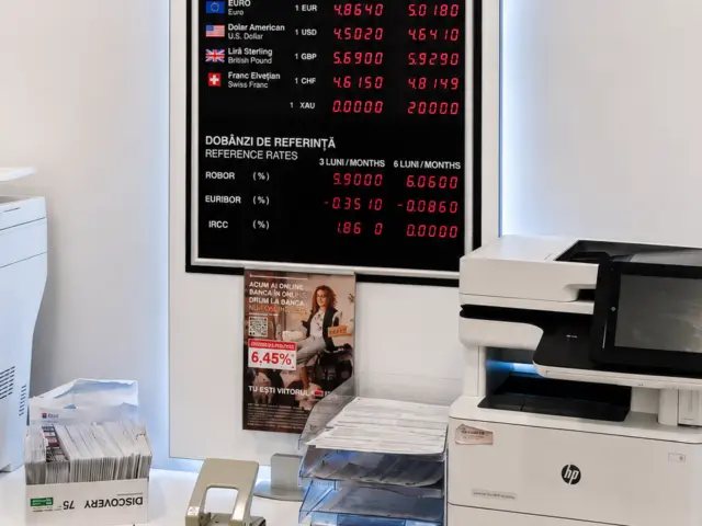 Afișaj electronic BRD cu cursuri valutare și dobânzi de referință, montat într-un spațiu interior.