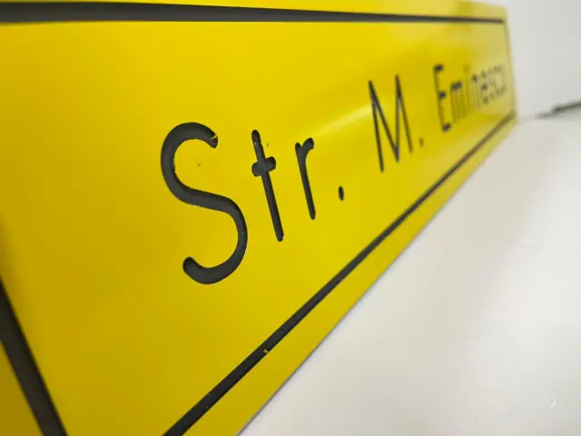 Indicator galben pentru Str. M. Eminescu, cu text și chenar negre, surprins din lateral.