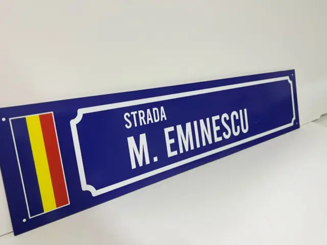 Indicator stradal albastru pentru Strada M. Eminescu, cu tricolor vertical și chenar alb decorativ.