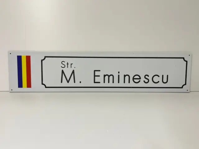 Indicator alb pentru Str. M. Eminescu, cu tricolorul României și chenar negru decorativ.