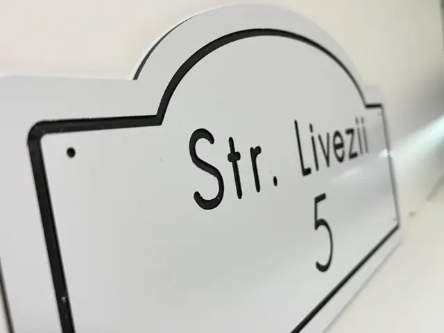 Plăcuță albă cu profil decorativ și contur negru, inscripționată „Str. Livezii 5”, montată pe perete.