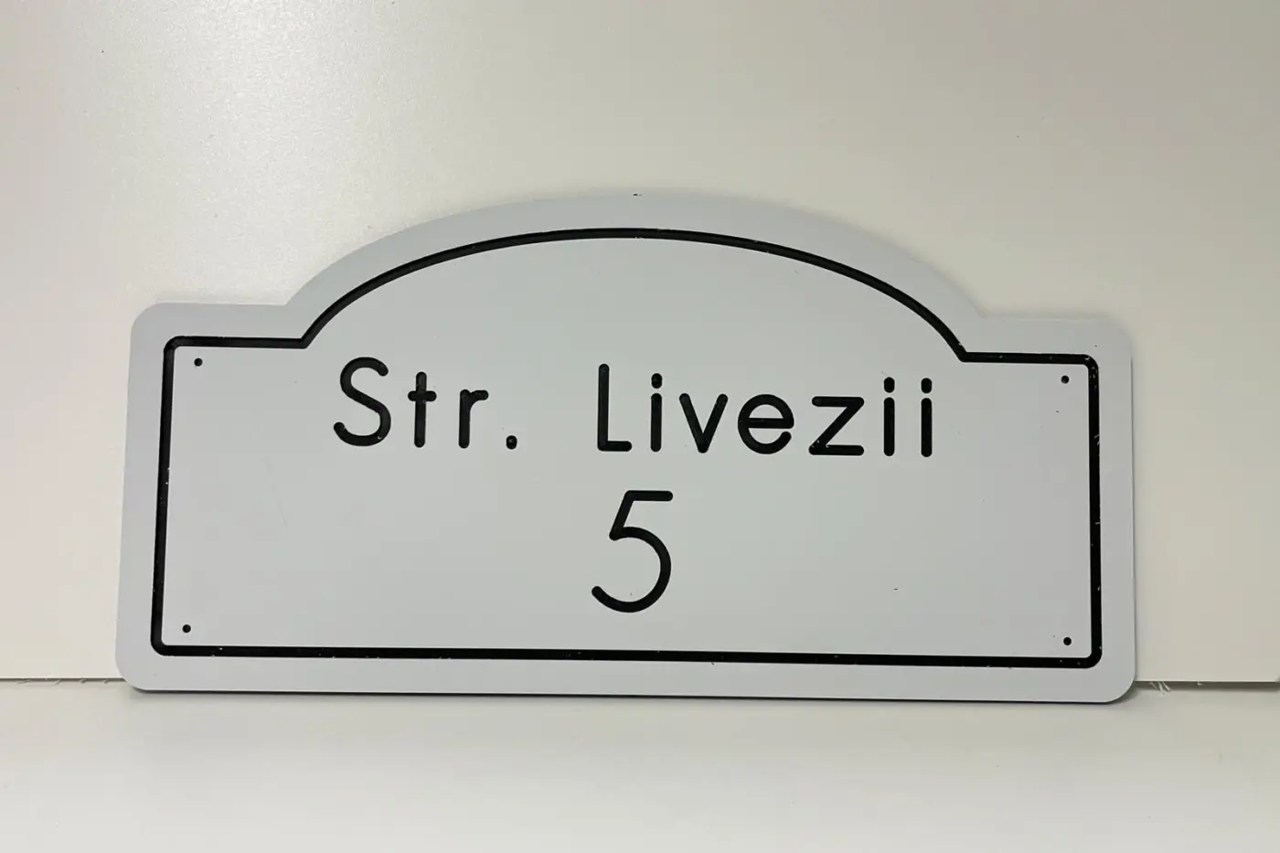 Plăcuță albă de adresă, cu partea superioară arcuită, inscripționată „Str. Livezii” și numărul 5.