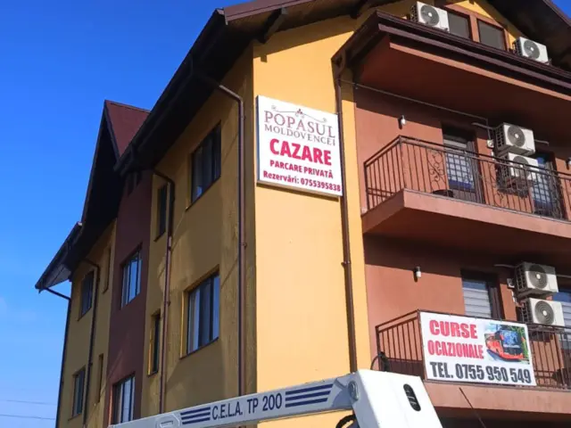 Firmă Popasul Moldovencei pentru cazare și parcare privată, montată la etaj pe fațada clădirii.