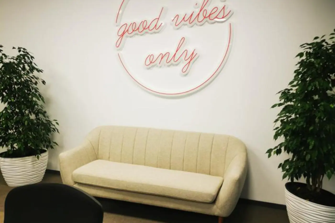 Semn circular roz din Neon Flex, cu mesajul „good vibes only”, montat deasupra unei canapele.