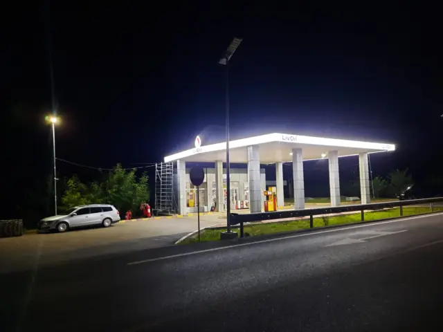 Sigla și numele LivOil, iluminate pe copertina unei benzinării surprinse noaptea.