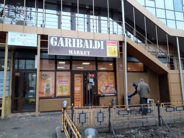 Firma Garibaldi Market montată deasupra intrării, pe fațada unui spațiu comercial cu vitrine colantate.