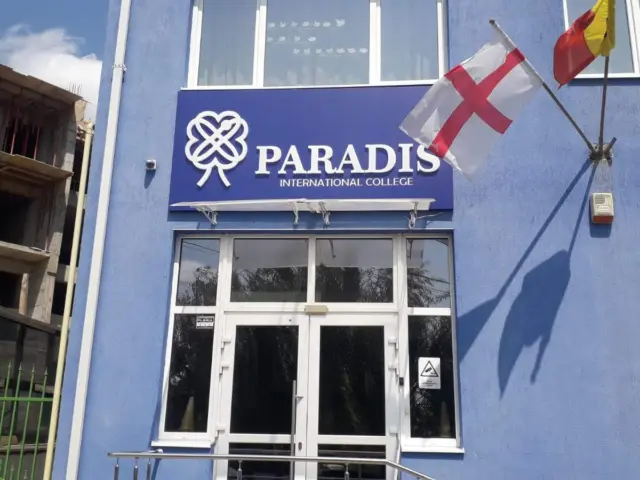 Firmă Paradis International College montată deasupra intrării, pe fațada albastră a clădirii.
