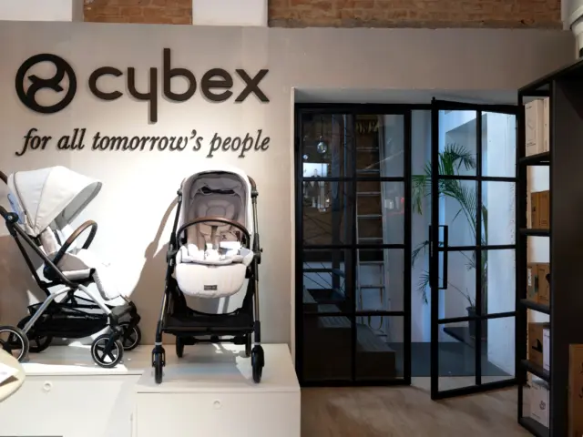 Logo Cybex și slogan montate pe peretele unui showroom cu cărucioare expuse